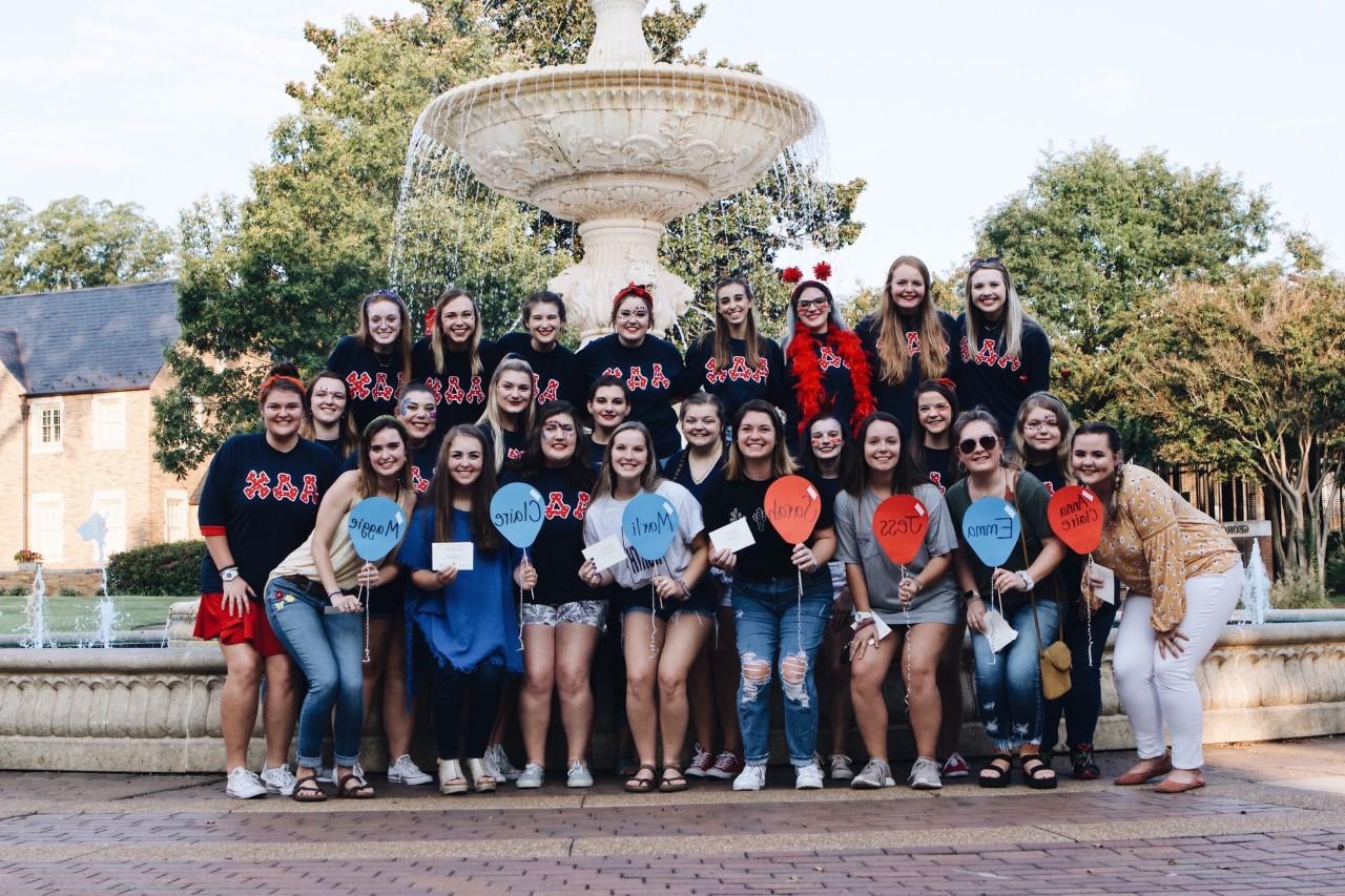 Members of Alpha Delta Chi pose for a group photo in front of the fountain
